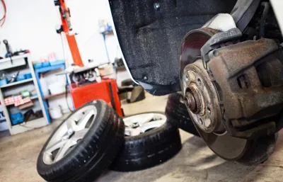Véhicule soulevé dans l’atelier, roues démontées et disque de frein à nu.